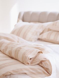 an unmade bed with striped sheets and pillows