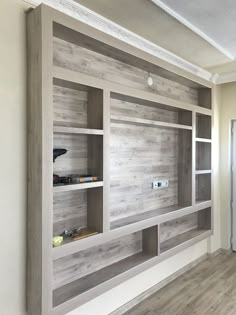 an empty room with wooden shelves and white paint on the walls, along with wood flooring