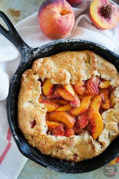 a peach cobbler in a cast iron skillet with fresh peaches on the side