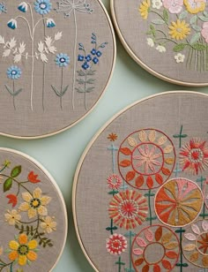 four embroidered hoops with flowers on them sitting on a table next to each other