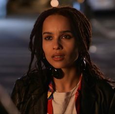 a woman with dreadlocks on her head looking off to the side at night