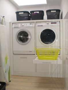 a washer and dryer sitting in a room next to each other with laundry baskets on top