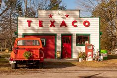 an old red truck parked in front of a texaco building with stars on it