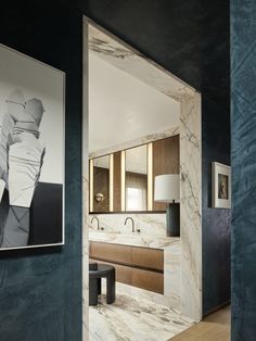 a bathroom with blue walls and marble counter tops, along with a painting on the wall