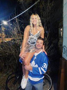 a man standing next to a woman on top of a bike