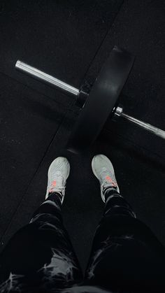 a person standing in front of a barbell with their feet on the ground next to it