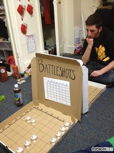 a man sitting on the floor next to a box with candles in it that says battleshots