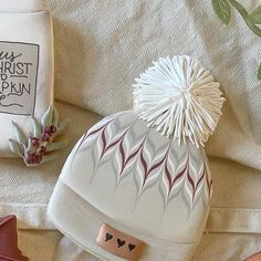 a white knitted hat sitting on top of a bed next to other items and decorations