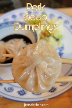 some dumplings are sitting on a plate with chopsticks