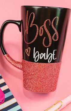 a black and pink coffee mug with the word boss on it next to a pen