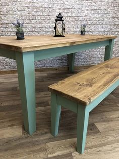 a wooden table and bench in front of a brick wall