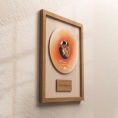 a wooden frame holding a cd with a picture on it and a plaque underneath the disc