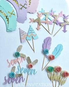 there are some cupcake toppers with flowers and feathers on them in pastel colors