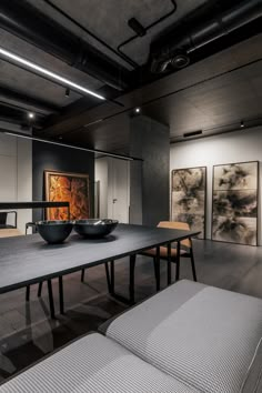 a large table with two bowls on it in a room filled with paintings and couches