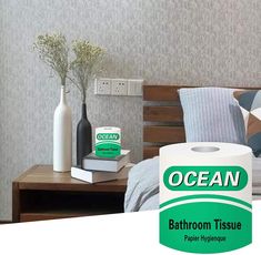 a bathroom tissue sitting on top of a bed next to a vase with flowers in it