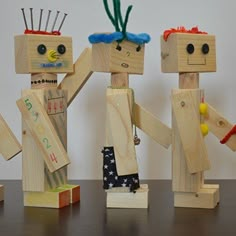 three wooden dolls made to look like they are holding hands with each other on a table