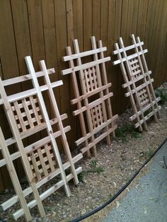 four wooden chairs are lined up against a fence outside on the ground next to each other