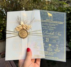 a person holding up a wedding card with a gold seal on the front and back