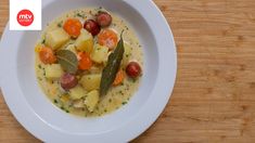 a white bowl filled with food on top of a wooden table