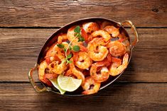 a pan filled with cooked shrimp and garnished with lime