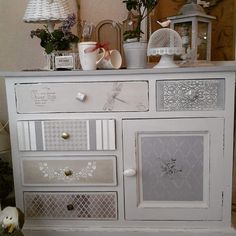 a white dresser with lots of drawers and decorations on it's top shelf next to a mirror