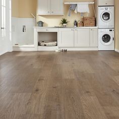 an empty kitchen with white cabinets and wood flooring in the center is a washer and dryer