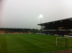 an empty soccer field with fans in the stands and fog on the ground at night