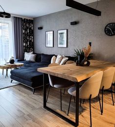 a living room filled with furniture and a wooden table in front of a large window