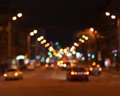 cars driving down the street at night with blurry lights in the backround