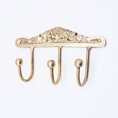 a gold coat rack with three hooks on it