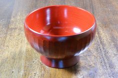 a red bowl sitting on top of a wooden table