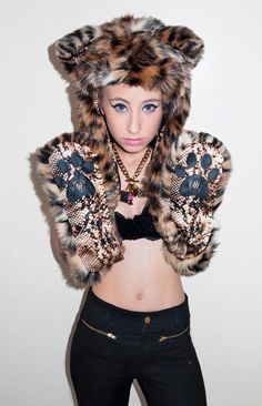 a woman wearing a leopard print jacket and black pants with her hands on her hips