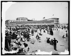 an old black and white photo of people on the beach in front of a building