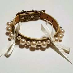 a close up of a bracelet with pearls and bows on it's end,