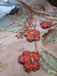 an embroidered table cloth with flowers and leaves on it