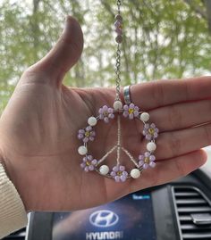 a person holding a peace sign made out of beads and flowers in their hand,