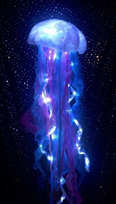 a jellyfish with blue and purple lights on it's head in the dark