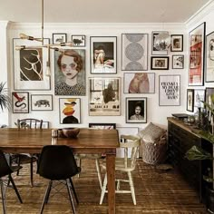 a dining room filled with lots of pictures on the wall and wooden table surrounded by chairs