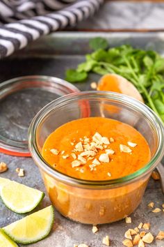 a glass bowl filled with carrot soup and garnished with peanuts