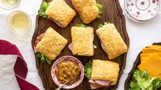 ham and cheese pastries on a wooden platter with a bowl of sauce next to them