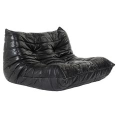 a black leather lounge chair on a white background with the seat folded back and foot rest down