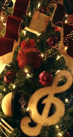 a christmas tree decorated with gold and red ribbons, ornaments and decorations on top of it