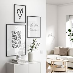 a living room with white furniture and pictures on the wall