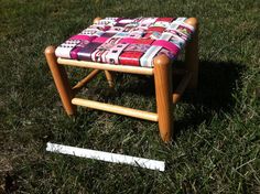 a small wooden stool sitting on top of a lush green field next to a ruler