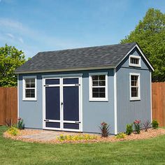 a backyard shed with a blue door and windows