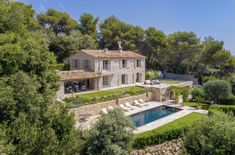 an aerial view of a house with a pool in the foreground and trees surrounding it