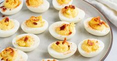 several deviled eggs on a plate with bacon sprinkled on the top and sides