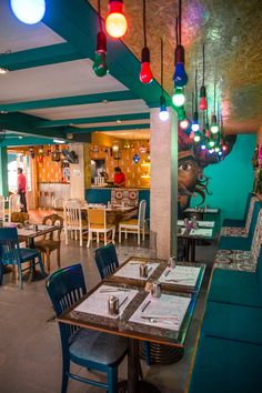 the interior of a restaurant with tables and chairs, lights hanging from the ceiling, and artwork on the walls