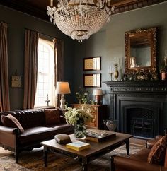 a living room filled with furniture and a chandelier hanging from the ceiling over a fire place