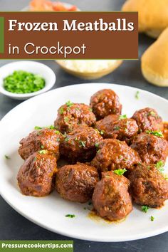 some meatballs are on a white plate with green onions and peas next to bread rolls